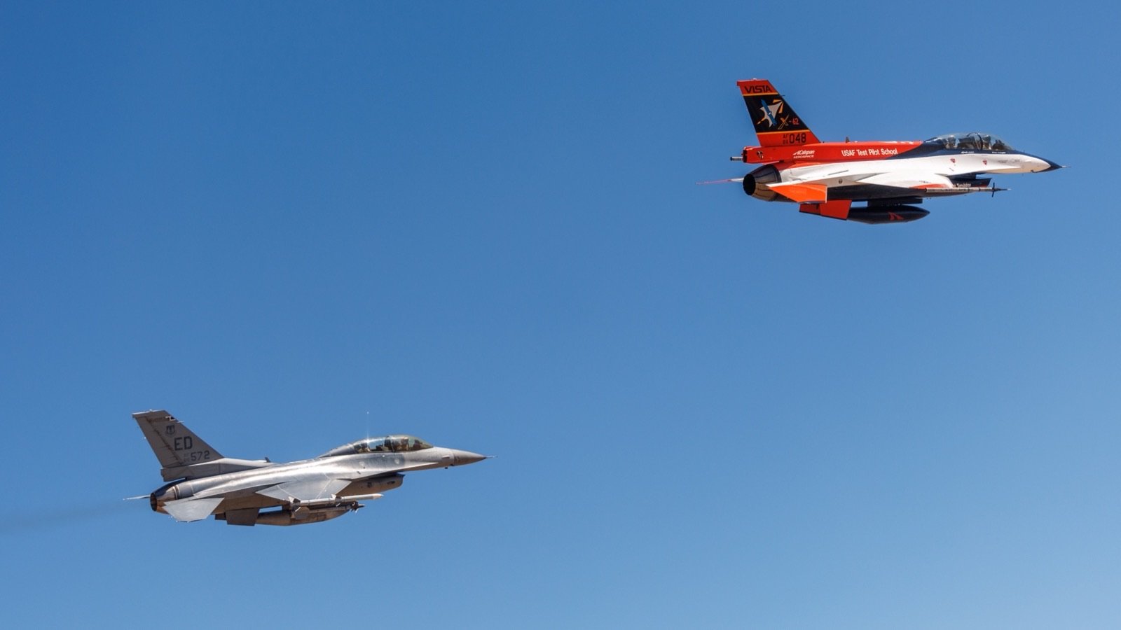 Pomarańczowo-biały X-62A VISTA w locie obok szarego seryjnego F-16 nad bazą Edwards